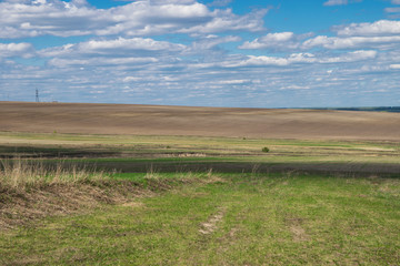 Obraz premium plowed field in spring and sky with clouds