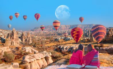 Hot air balloon flying over spectacular Cappadocia - Girls watching hot air balloon at the hill of Cappadocia 