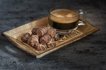 Schokoladen Pralinen mit einer Tasse Kaffee liegen in einer braunen Schale