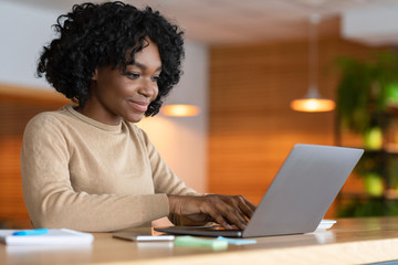 Female blogger working at cafe, typing on laptop