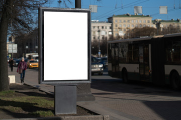A vertical city billboard standing on a green lawn behind a curb. With a white space for posters copy space
