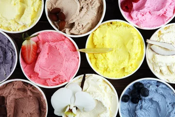 Verschiedene Eissorten mit frischen Heidelbeeren, Erdbeeren, Kiwi, Zitrone, Vanille auf rustikalem Hintergrund. Sommer und süßes kaltes Eis © beats_