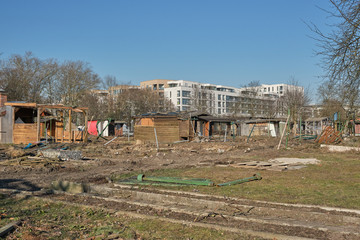 Destroyed gardens in front of new buildings under a blue sky