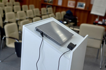 laptop with charger on the podium in the conference room. rows of seats for spectators. report. presentation. education. development