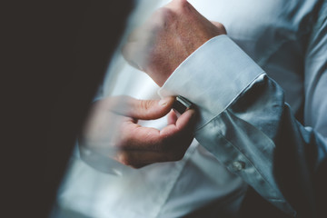 men's hands in a white shirt adjusting red cufflinks