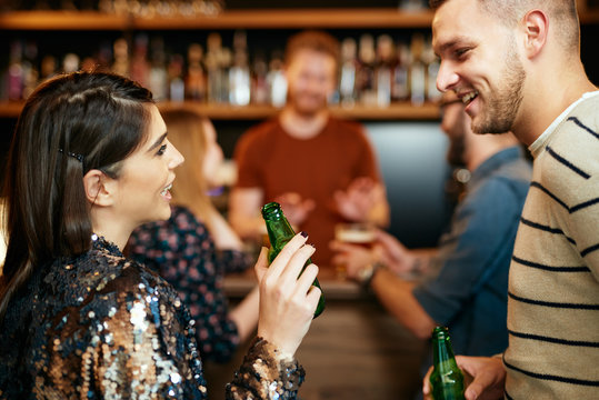 Group of friends drinking beer, chatting and having good time at pub. Night out.