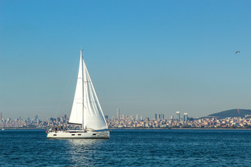 One White Yacht on the blue sea. Beautiful big city Istambul, Turkey with modern buildings