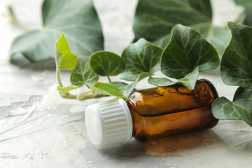 A leaf of ivy and syrup in a bottle on a light concrete table. Production of cough medicine with ivy extract. pharmaceutical industry