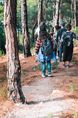 Obraz premium Sports and tourism. A group of people coming down the slope with pine trees. Rear view