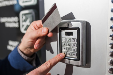 Man hand pressing the security code combination and using key card to unlock the door