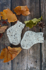 Chunky and warm hand-knitted baby socks on dark wooden background