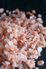 Pink Himalayan salt on slate plate. Black background, high resolution, hard light