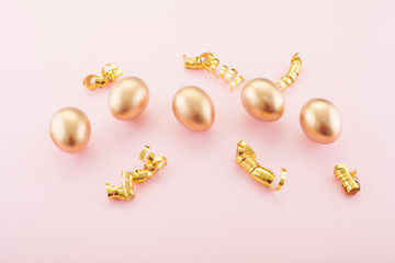 Golden eggs on a pink background, decorated with gold ribbons. The concept of Passover and the holiday symbol.
