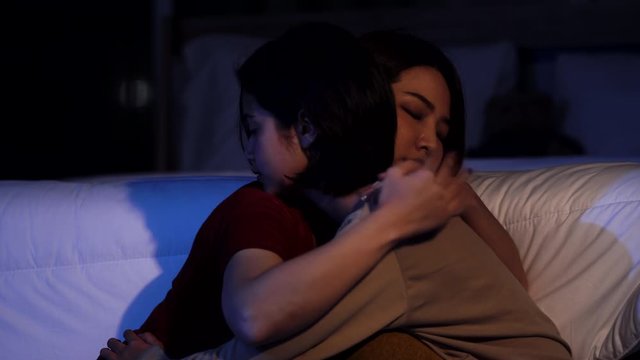 4K Young beautiful Asian woman comforting her sad friend at night. Woman hugging and consoling her depressed girls friend in bedroom.  Teenage problems and depressed mental health issue concept.