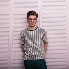 Pretty sexy young man hipster in fashionable glasses with a hairstyle in a trendy striped t-shirt...