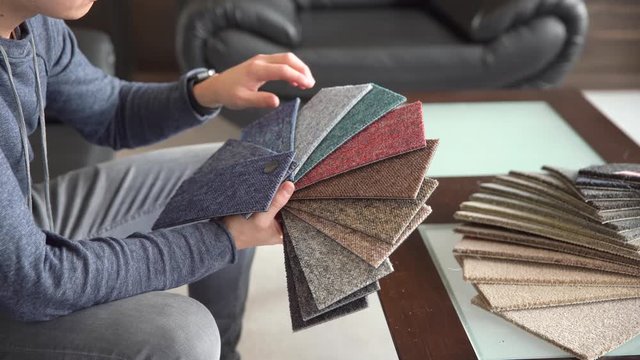 the man chooses the color of the new carpet according to the pattern book in the flooring shop