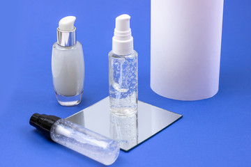 Cosmetic bottles with serum, gel, face cream on a blue background. Skin cosmetics, minimalism. The concept of salon procedures.