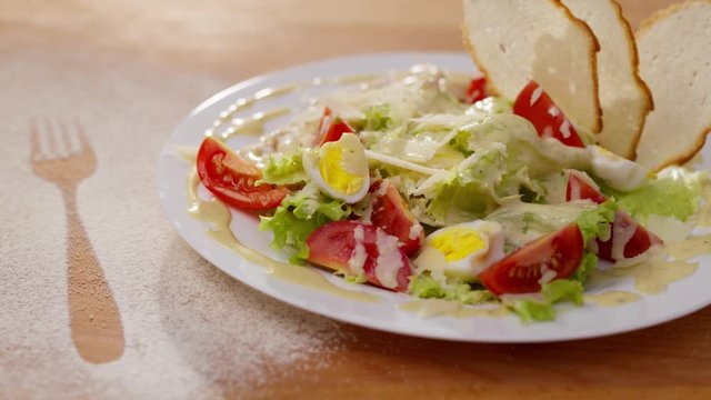 Appetizing and healthy fresh made salad served in a restaurant. Rotation close-up shot of tasty salad with eggs, tomato slices, leaves and bread toasts. Food concept.