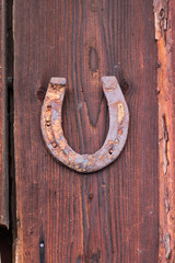 old rusty iron horseshoe nailed to an old wooden board on a door or wall