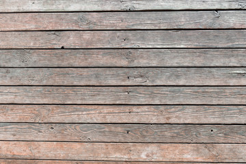 Close-up of wooden texture of wall boards driven in with rusty nails, weathered planks with deep cracks and worn brown paint. Abstract rustic background for design, blank template