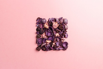 Frame made of purple and pink dry flowers, branches, leaves and petals on pastel pink background. Colorful background image. Top view. Flat lay. Copy space. Art concept. Color trends 2020