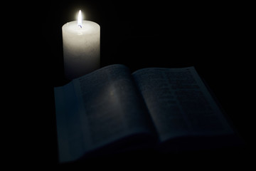 Burning candle and opened bible, book. The concept of faith in God, Christianity, religion.