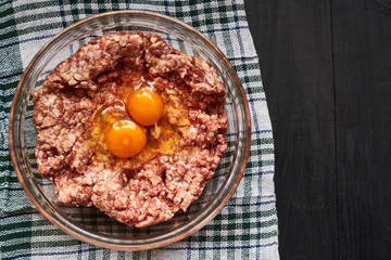 Minced meat with raw egg in a plate. Cooking meat products.