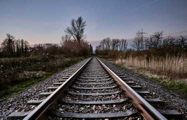 Fototapeta na wymiar Railroad track in a rural area in front of the blue sky