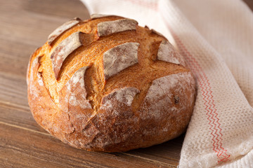 Whole round loaf of artisan sourdough bread on a wooden surface