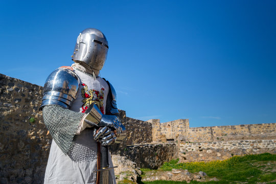Caballero con armadura medieval posando con su espada en un castillo