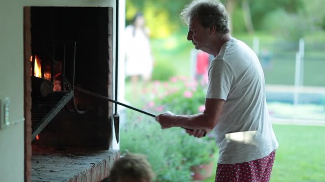 Retired senior man preparing BBQ, traditional uruguayan parilla grill