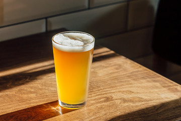 A glass of beer on a wooden table.