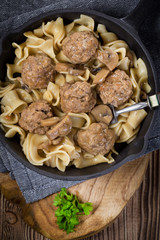Pork meatballs with noodles in a cast iron skillet.
