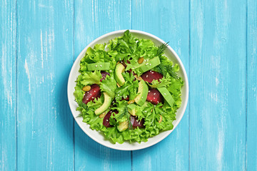 Vegan beetroot salad, avocado, lettuce, sunflower, sesame seed. Home made vegetarian beet salad. Clean eating concept on wood background. Tasty fresh beetroot veg mix leaves dish. Top view.