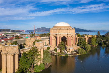 Fototapeta premium Palace of Fine Arts, San Francisco, California, aerial view with Golden Gate Bridge in the background. Morning light, copy space in sky. Palace reflection in water. Blue sky, red bridge.