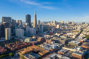 Fototapeta na wymiar San Francisco aerial view of downtown at sunrise. Drone view facing downtown. Blue sky, golden light copy space in sky. Embarcadero and North Beach area in foreground.