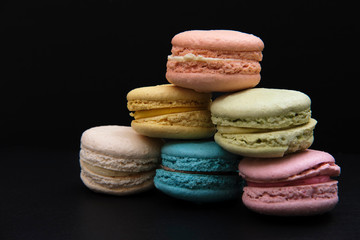 Sweet and colourful french macaroons on dark black background, Dessert.