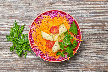 Vegan salad with red cabbage, cherry tomatoes, cucumber, carrot. Home made vegetarian food. Clean eating concept on wood background. Tasty mix vegetable fresh cabbage salad. Top view.