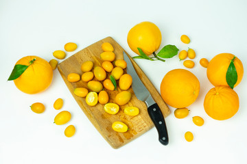  cut kumquat and orange on a wooden board. Fresh fruits, food on a white background.
