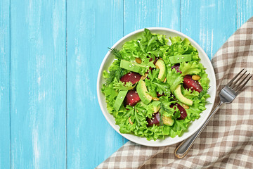 Vegan beetroot salad, avocado, lettuce, sunflower, sesame seed. Home made vegetarian beet salad. Clean eating concept on wood background. Tasty fresh beetroot veg mix leaves dish. Top view.