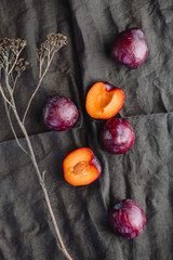 High angle view of fresh purple plum on a dark linen. Food photography still life.