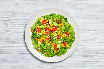 Vegan greens salad, chickpeas, lettuce, arugula, cherry tomatoes. Home made vegetarian green salad. Diet, vitamin food concept on wood. Tasty veg mix leaves salad in bowl. Top view.