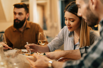 Young woman eating dinner with her friends at home.