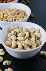 superfood concept, cedar, walnuts, cashew nuts in a plate on a black background