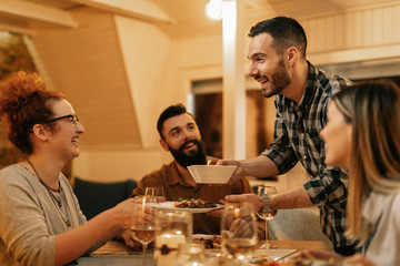 Group of happy friends having fun during dinner in dining room.