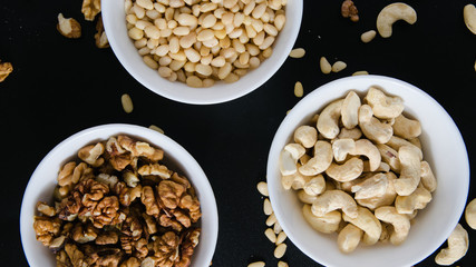 superfood concept, cedar, walnuts, cashew nuts in a plate on a black background