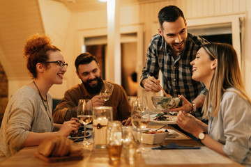 Group of happy friends having fun while eating dinner in dining room.