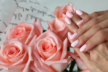 Beautiful pink matte manicure against the background of pink roses.
