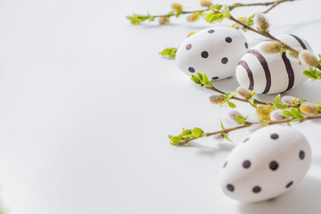 Composition with green buds on branches, easter eggs on a light background