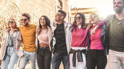 Unity and togetherness concept of multiracial young people embracing together. Friends from different race walking together hands on shoulders outdoors in the street.